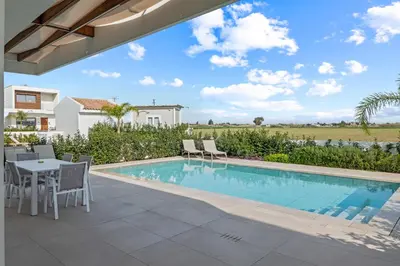 a patio with a table and chairs next to a swimming pool at Serenity Waves Villa 20 in Larnaka