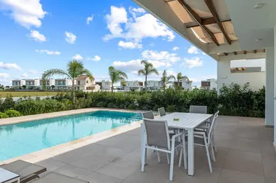 a patio with a table and chairs next to a swimming pool at Serenity Waves Villa 20 in Larnaka