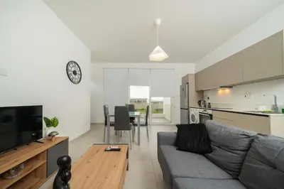 a living room with a gray couch and a kitchen at 1 bedroom flat in Aglatzia in Aglantzia