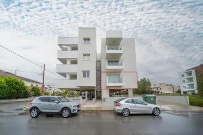 two cars parked in a parking lot in front of a building at 1 bedroom flat in Aglatzia in Aglantzia