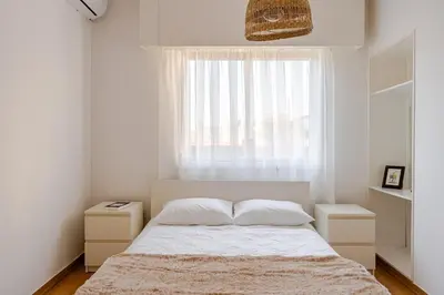 a white bedroom with a bed and a window at Central Escape in Limassol