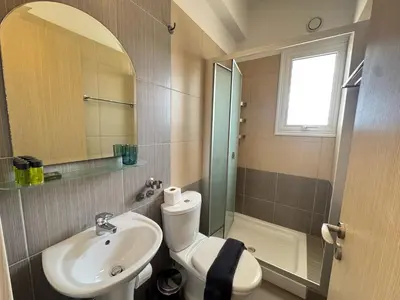 a bathroom with a sink and a toilet and a mirror at Wealthystays 3BR Terrace BBQ Villa with pool in Liopetri