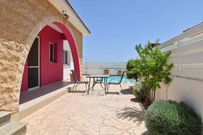 a patio with chairs and a table on a building at Wealthystays 3BR Terrace BBQ Villa with pool in Liopetri