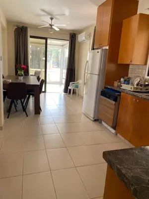 a kitchen and dining room with a table and refrigerator at A sea breeze villa in Pyla