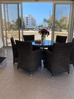 a dining room table with chairs and a vase of flowers at A sea breeze villa in Pyla