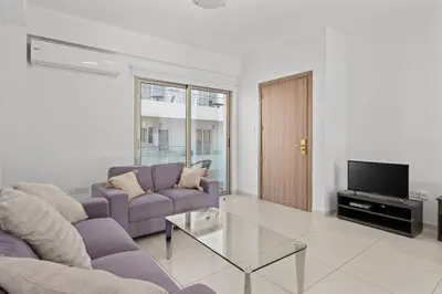 a living room with a purple couch and a tv at Downtown Comfort Apartment in Larnaka