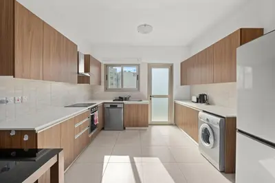 a kitchen with wooden cabinets and a washer and dryer at Downtown Comfort Apartment in Larnaka
