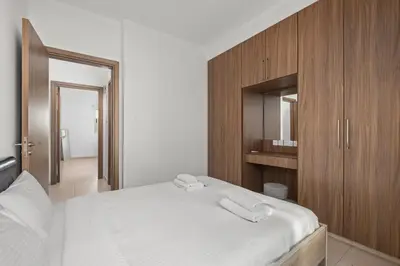 a bedroom with a white bed and wooden cabinets at Downtown Comfort Apartment in Larnaka