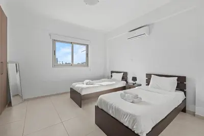a white room with two beds and a window at Downtown Comfort Apartment in Larnaka