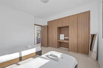 a bedroom with two beds and a wooden cabinet at Downtown Comfort Apartment in Larnaka