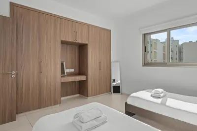 a bedroom with two beds and wooden cabinets at Downtown Comfort Apartment in Larnaka