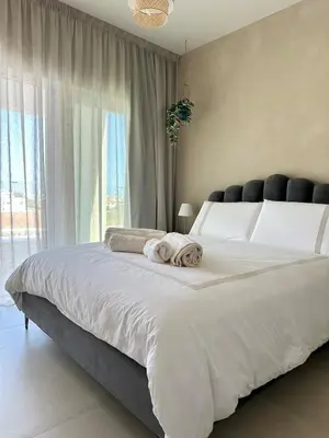 a bedroom with a large white bed with towels on it at Bella at Mythical Seas in Paralimni