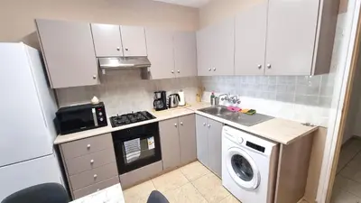 a small kitchen with white cabinets and a washer and dryer at 5 Min Walk to Beach, Perfect Seaside Escape in Larnaka