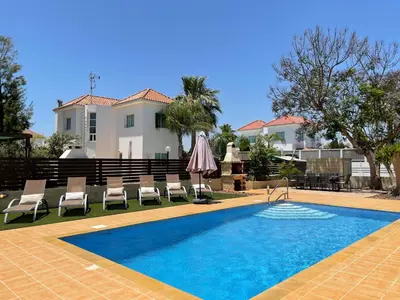a swimming pool with chairs and a house at Maeva villa in Ayia Napa