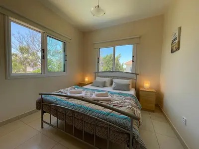 a bedroom with a bed with two windows at Maeva villa in Ayia Napa