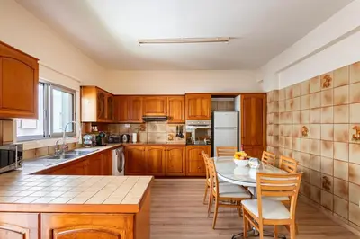 a kitchen with wooden cabinets and a table and chairs at Central, renovated, fully equipped, spacious 3BD in Strovolos