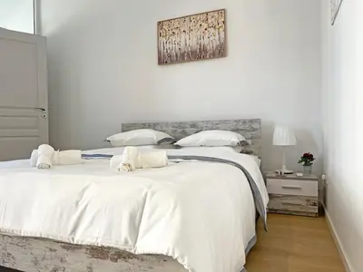 a white bedroom with a large bed with white sheets at Albert's Apartment Center 101K in Larnaka