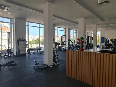 a gym with treadmills and exercise equipment and windows at Mythical Sands Resort - Africa in Protaras