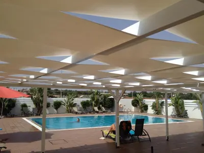 a person sitting in a chair next to a swimming pool at Mythical Sands Resort - Africa in Protaras