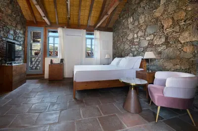 a bedroom with a bed and a couch and a chair at Lyhnos in Askas