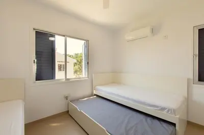 a white room with a bed and a window at Family Fig Tree Bay House in Protaras