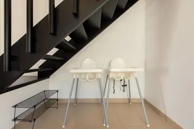two white stools in a room with stairs at Family Fig Tree Bay House in Protaras