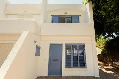 a white house with a blue door and a window at Family Fig Tree Bay House in Protaras
