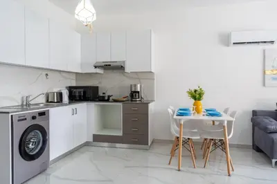 a kitchen with a sink and a table with chairs at Infinity - One-Bedroom Apt W Terrace in Larnaca in Larnaka