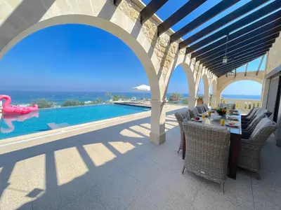 a patio with a table and chairs next to a swimming pool at Sunrise Dream Villa-Protaras in Protaras