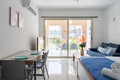 a living room with a blue couch and a table at Sunny Side Studio W Terrace in Larnaca in Larnaka