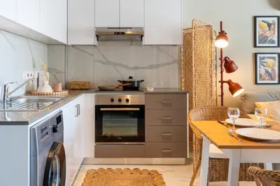 a kitchen with a stove and a dining table at Sundrop - 1-Bedroom Apt W Terrace in Larnaca in Larnaka