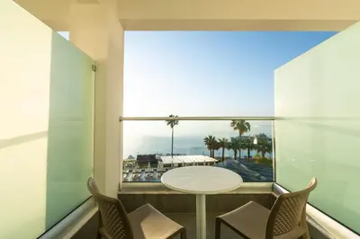 a balcony with a table and chairs and a view of the ocean at Evalena Beach Hotel in Protaras