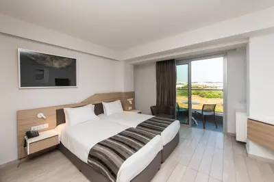 a hotel room with a bed and a large window at Evalena Beach Hotel in Protaras