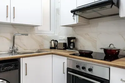 a kitchen with white cabinets and a stove top oven at Vibe - 1 Bedroom Apartment W Balcony in Larnaca in Larnaka