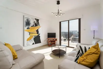 a white living room with a couch and a tv at Apartment Sun 'n Joy in Paralimni