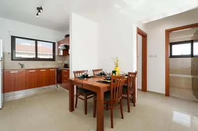 a kitchen and dining room with a wooden table and chairs at Apartment Sun 'n Joy in Paralimni