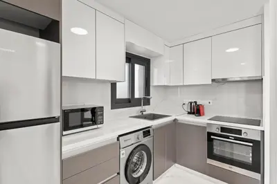 a kitchen with white cabinets and a washing machine at Maestro City Apartments in Larnaka