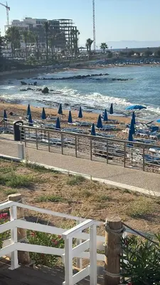 a beach with blue umbrellas and the ocean at Sunshine Villa Private Pool Luxury Garden 2' walk to Kalamies beach Pernera in Protaras
