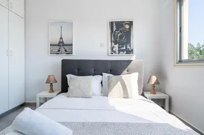 a white bedroom with a large bed with two tables at Liric - 3 Bedroom Apt W Balcony in Larnaca in Larnaka