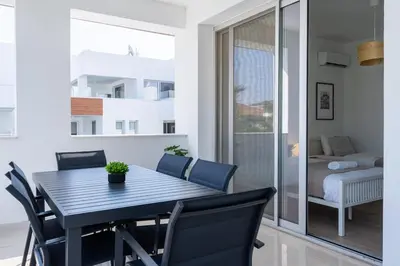 a dining room with a black table and chairs at Valleria - 2 BR Apartment W Pool in Larnaca in Larnaka