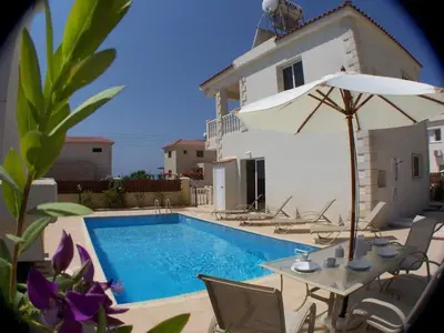 a swimming pool with a table and an umbrella at Villa Scarlett, Ayia Thekla in Ayia Napa