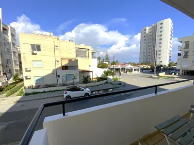 a white car parked on a city street with buildings at Cozy 2BR Beach Apt, Perfect for Getaways in Larnaka