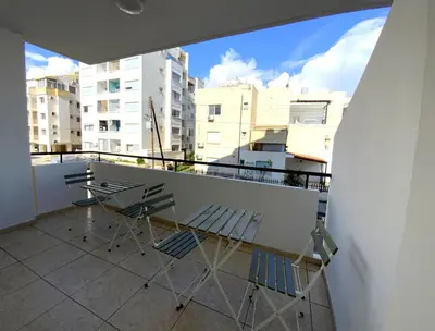 two chairs and a table on a balcony with buildings at Cozy 2BR Beach Apt, Perfect for Getaways in Larnaka