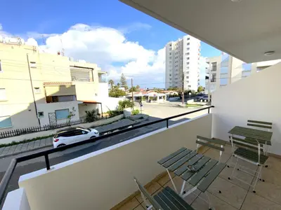 a balcony with chairs and a white car on a street at Cozy 2BR Beach Apt, Perfect for Getaways in Larnaka