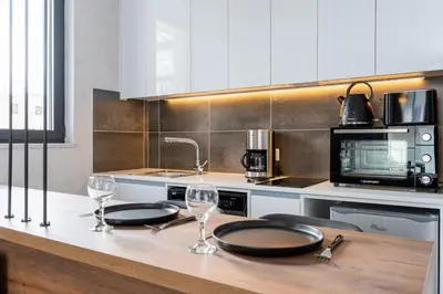 a kitchen with two plates and wine glasses on a counter at Dusk - Harmonic Studio by Plus 49 in Mackenzie in Larnaka
