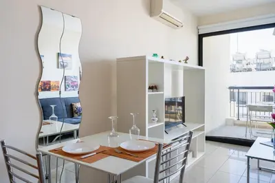 a dining room with a white table and chairs at Glade - 1 Bedroom Apt W Balcony in Larnaca in Larnaka