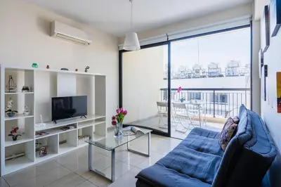 a living room with a blue couch and a glass table at Glade - 1 Bedroom Apt W Balcony in Larnaca in Larnaka