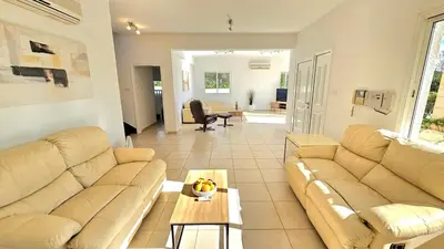 a living room with a couch and a table at White Cove Villa, Limassol in Pyrgos