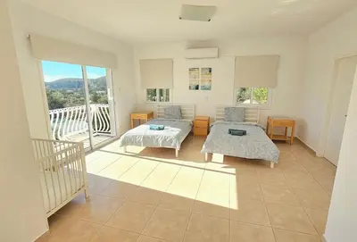 a living room with two beds and a balcony at White Cove Villa, Limassol in Pyrgos