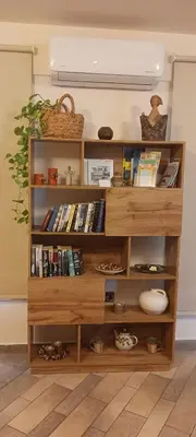 a wooden book shelf with books and other items at Plumeria Place Bright and spacious studio in Larnaka